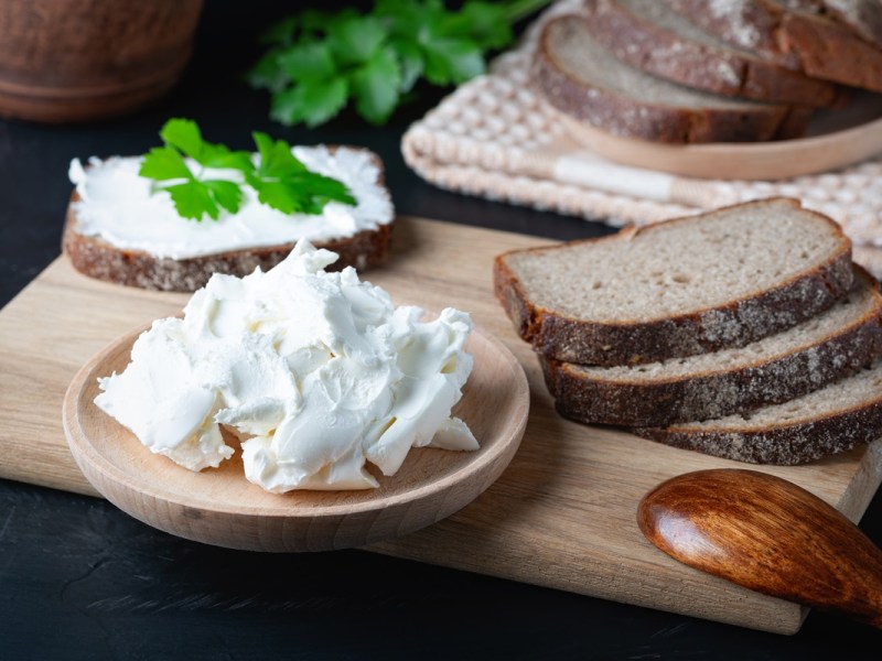 Quark selbst machen: Ein Teller mit selbstgemachtem Quark, daneben mehrere Brotscheiben.