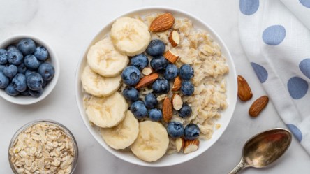 Eine Schüssel Soja-Porridge mit Bananen, Blaubeeren und Mandeln in der Draufsicht.