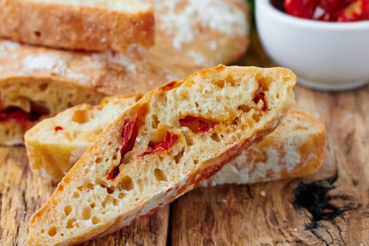 Mehrere Scheiben Tomaten-Ciabatta, die vor dem Brot liegen.