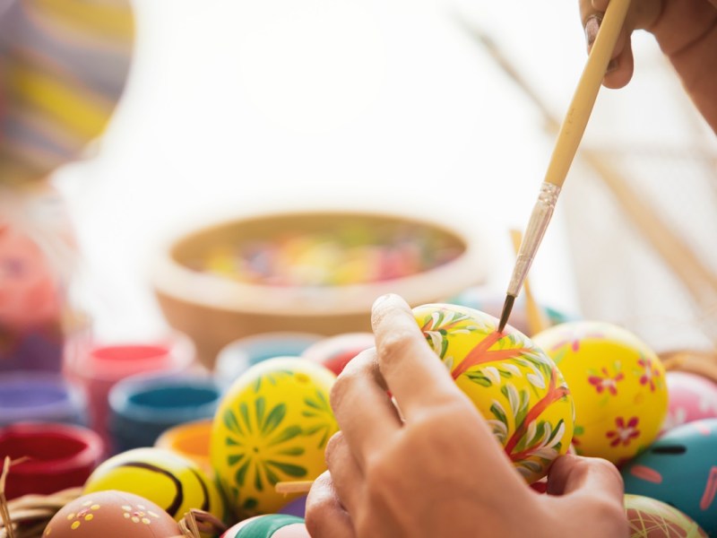 Warum gibt es Ostereier? Eine Frau bemalt Eier.