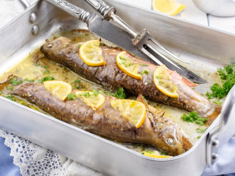 Zwei Backofen-Forellen in einer silbernen Ofenform.