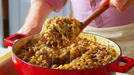 Eine Pfanne Cajun Style Dirty Reis, aus der mit einem Löffel eine Portion entnommen wird.
