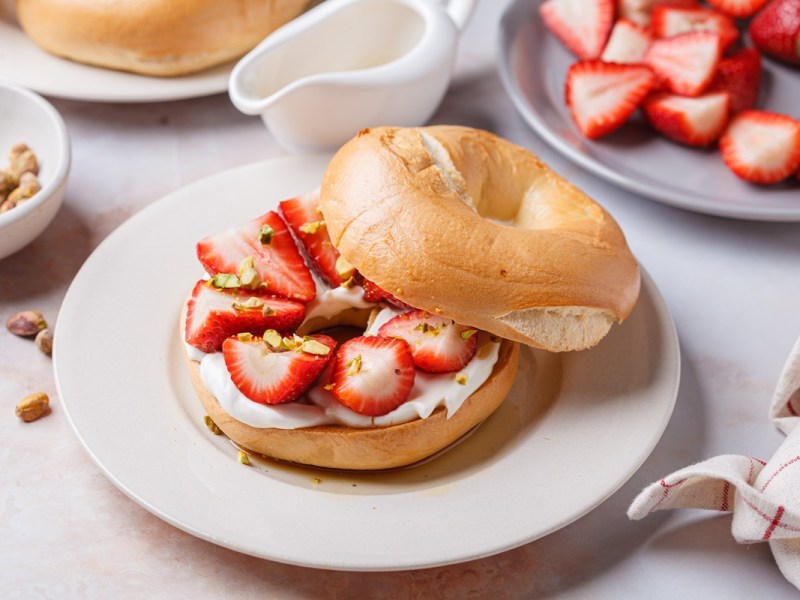 Ein Erdbeer-Ricotta-Bagel auf einem weißen Teller.