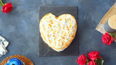 Ein Omelette SUrprise liegt auf einer Schieferplatte auf einer grauen Arbeitsplatte. Unten links im Bild steht eine Tasse und es liegt ein Küchentuch darüber. Oben links im Bild ist eine Rose. Rechts im Bild liegen weitere Rosen sowie eine Dose.