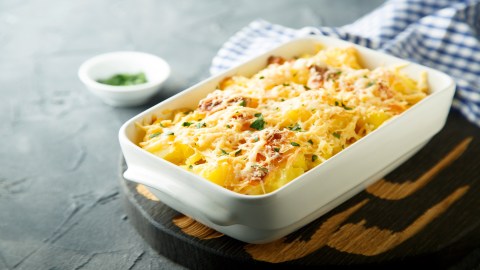 Überbackener Kohlrabi in weißer Auflaufform, die auf enem Brett steht.