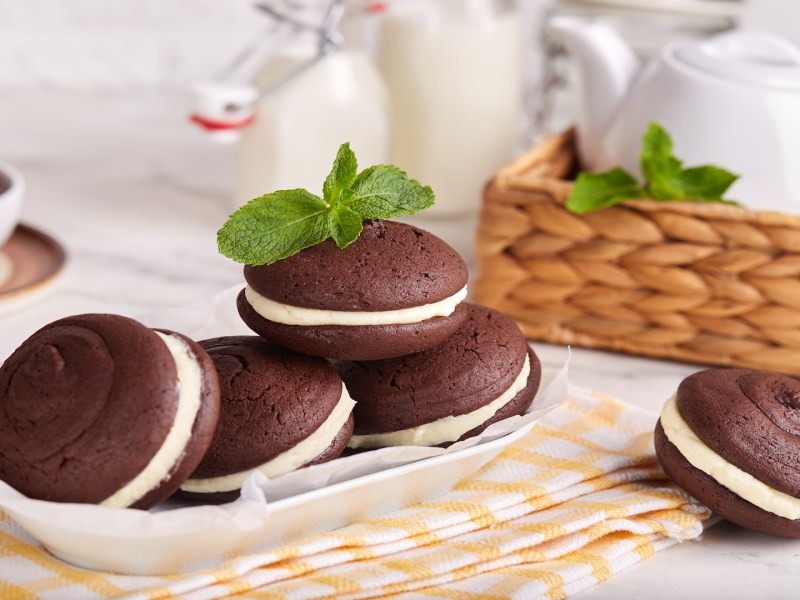 mehrere Whoopie Pies auf einem Tellerm drumherum etwas Geschirr.