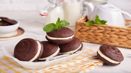 mehrere Whoopie Pies auf einem Tellerm drumherum etwas Geschirr.