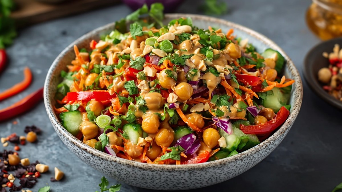 Eine Schüssel asiatischer Kichererbsensalat. Um die Schüssel liegen einige Zutaten verstreut.