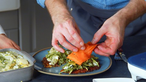 Berner Rösti mit Spargelsalat, auf die eine Scheibe Räucherlachs gelegt wird.