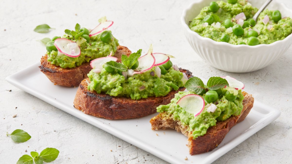 Drei Scheiben Erbsen-Bruschetta auf einem Teller.
