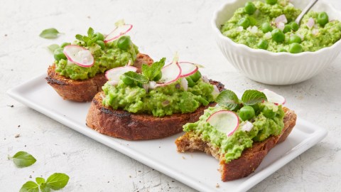 Drei Scheiben Erbsen-Bruschetta auf einem Teller.