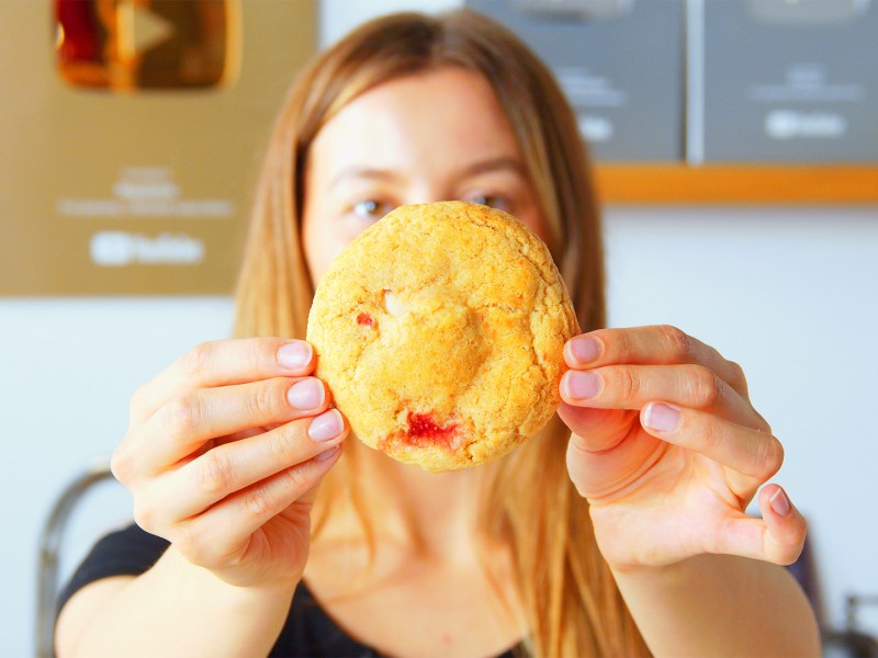 Gefüllte Erdbeer-Cheesecake-Cookies: Eine Köchin hält einen Keks in die Kamera.