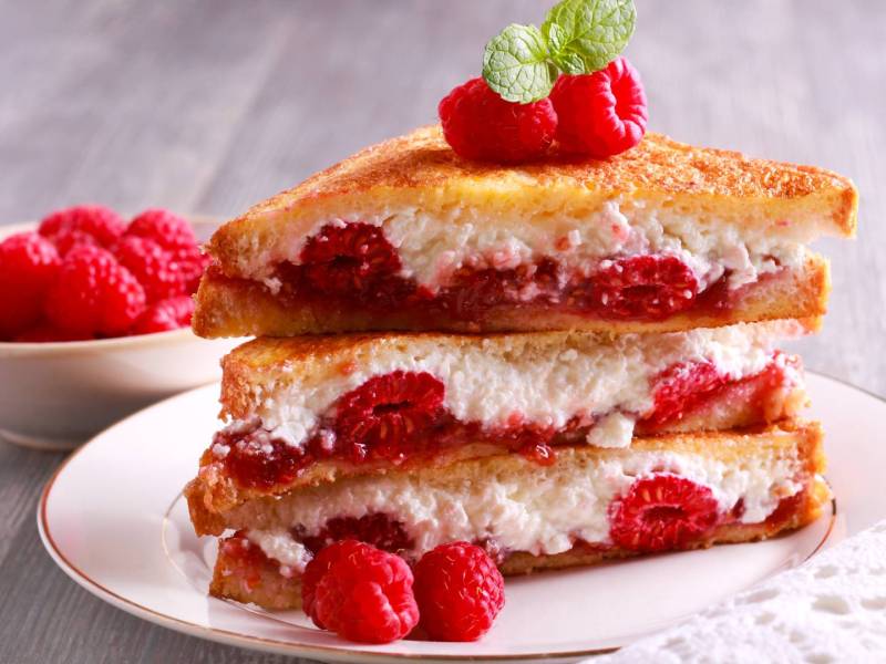 Ein Stapel gefüllter French Toast mit Ricotta und Himbeeren.