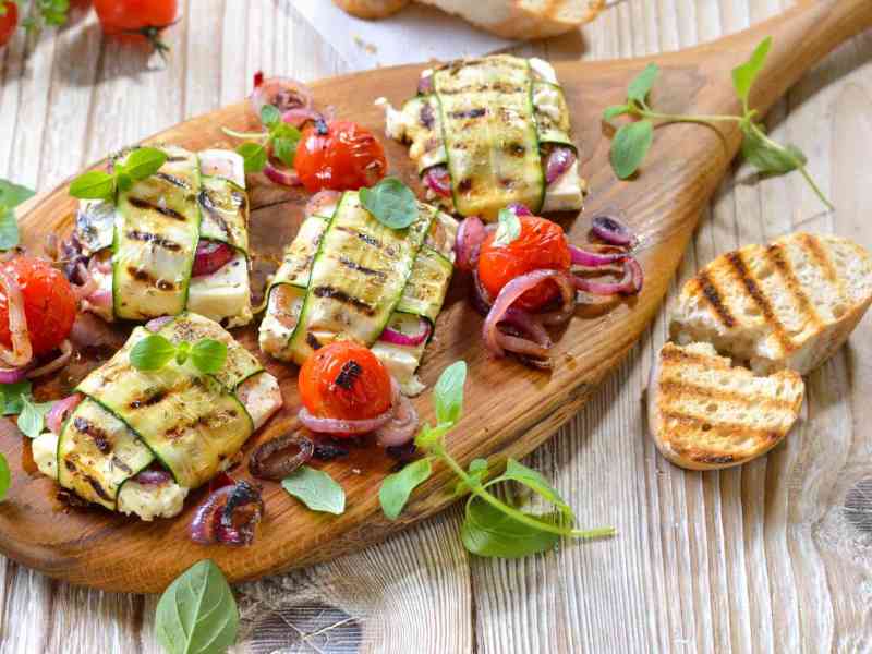 Gegrillte Zucchini-Feta-Päckchen, serviert auf einem Holzbrett.