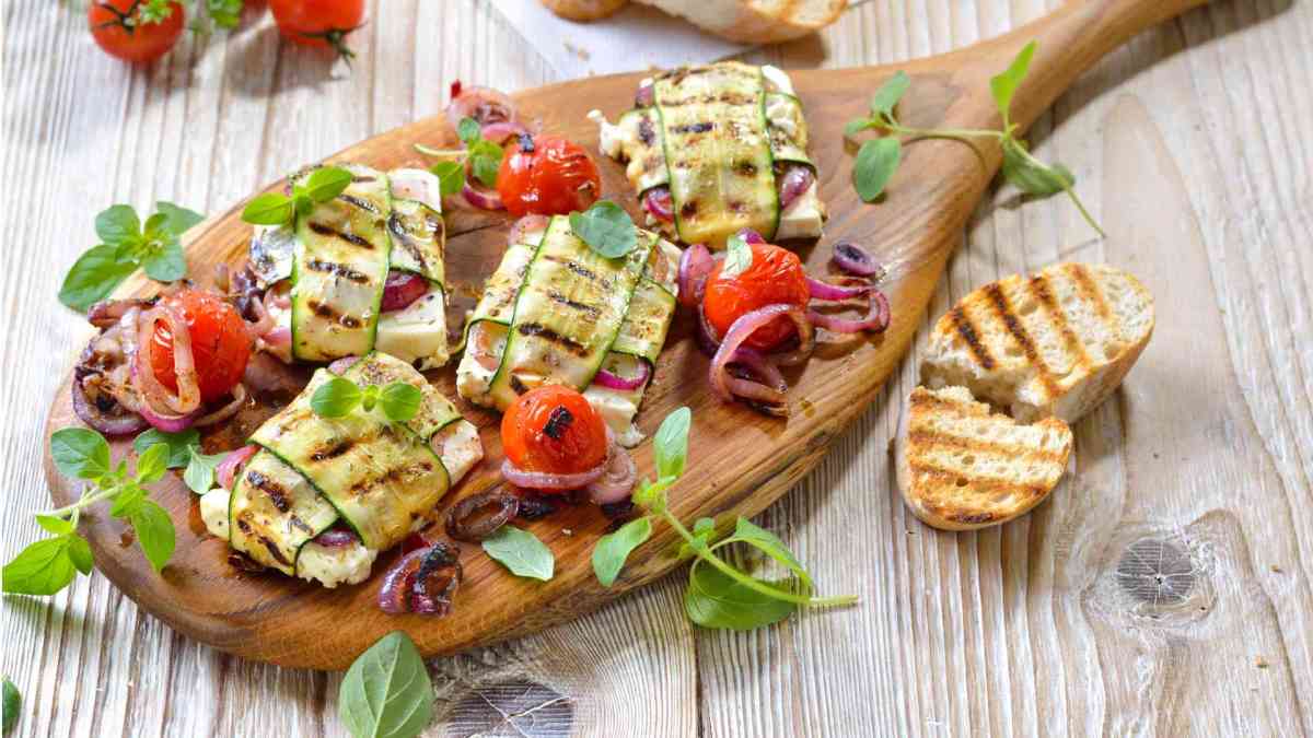 Gegrillte Zucchini-Feta-Päckchen, serviert auf einem Holzbrett.