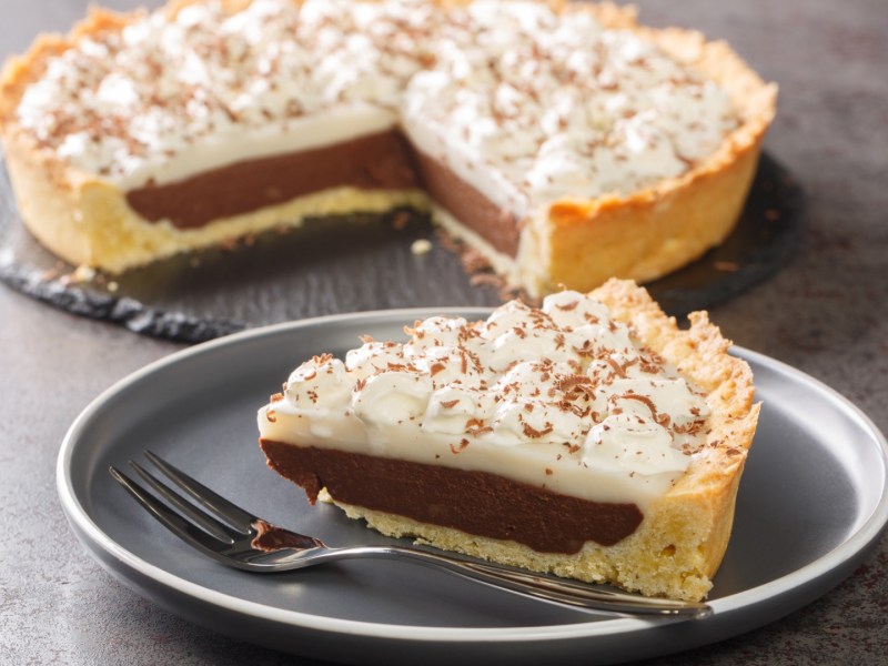 Ein Stück Haupia Pie auf einem Teller. Im Hintergrund steht der restliche Kuchen.