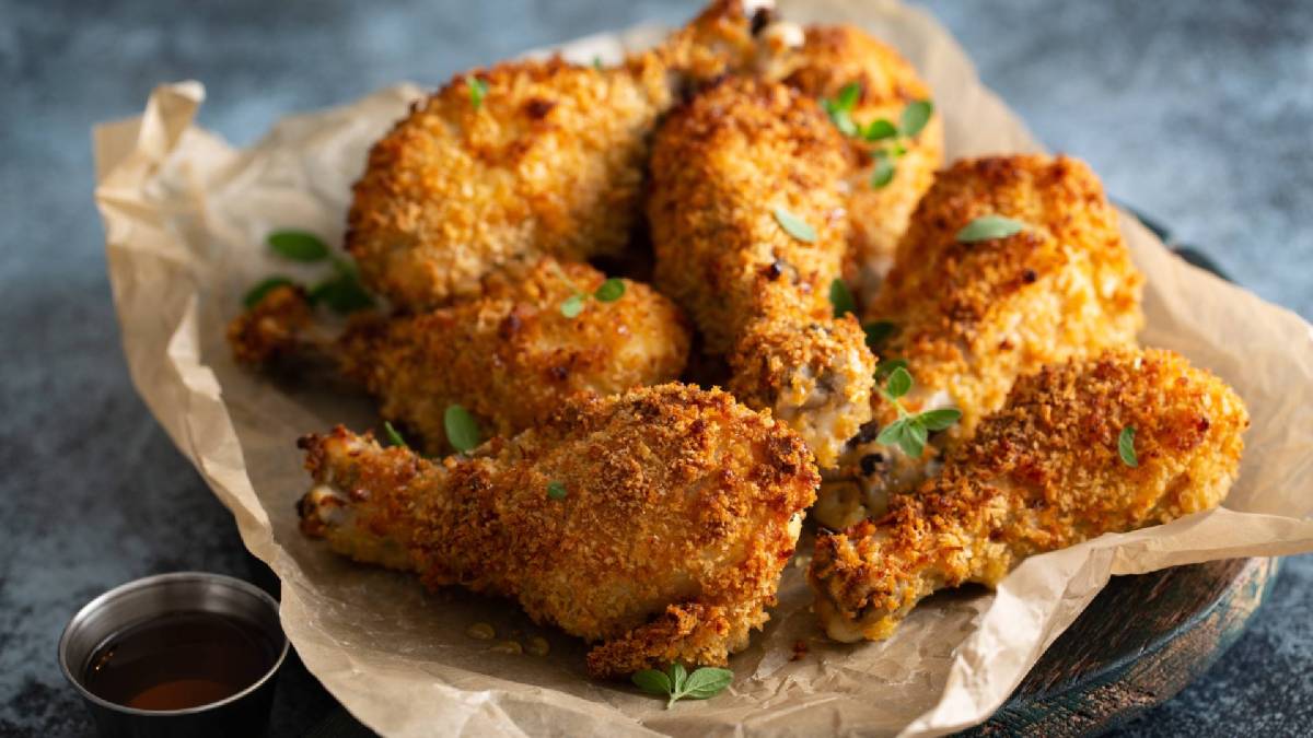 Einige Hähnchenkeulen, paniert mit Panko-Paniermehl, auf Backpapier.