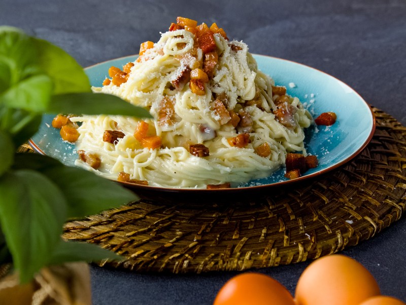 Italienische Spaghetti Carbonara auf einem blauen Teller.