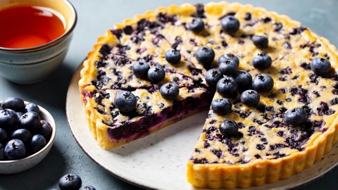 Eine Blaubeer-Vanille-Tarte, von der ein Stück entnommen wurde.