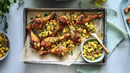 Ein Blech voller Hähnchenkeulen mit Mango-Kiwi-Salsa in der Draufsicht.