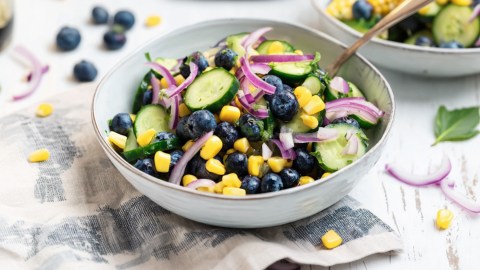 Eine Schüssel Heidelbeer-Mais-Salat mit einem Löffel drin.