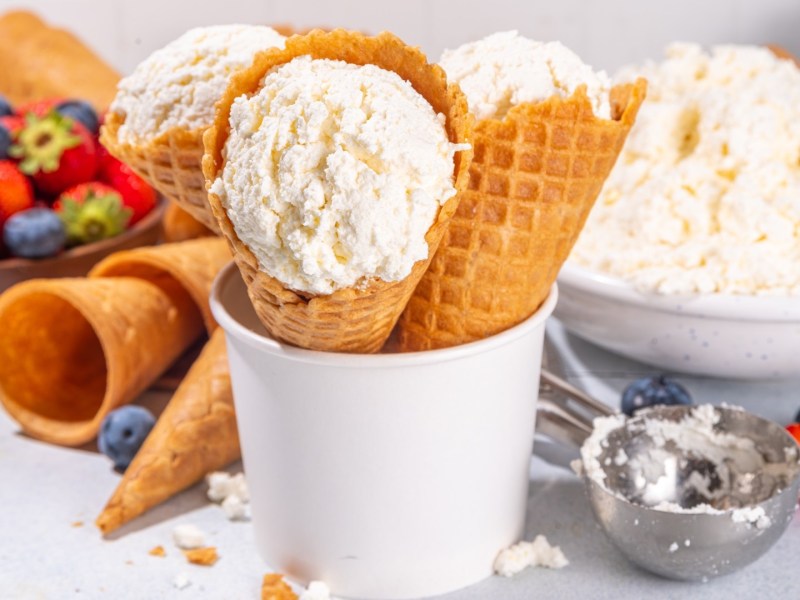 Mehrere Kugeln Hüttenkäse-Eis in Waffeln in einem Becher.