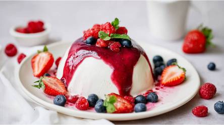 Teller mit einer Joghurtbombe mit Beerensoße und frischen Beeren