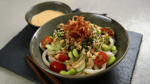 Eine Schale kalter Udon mit Sesamsoße auf einer Schieferplatte.