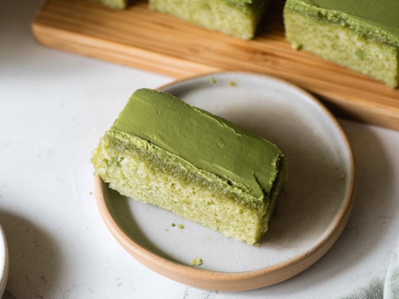 Ein Matcha Mochi Brownie auf einem Teller. Im Hintergrund sind weitere Brownies zu sehen.