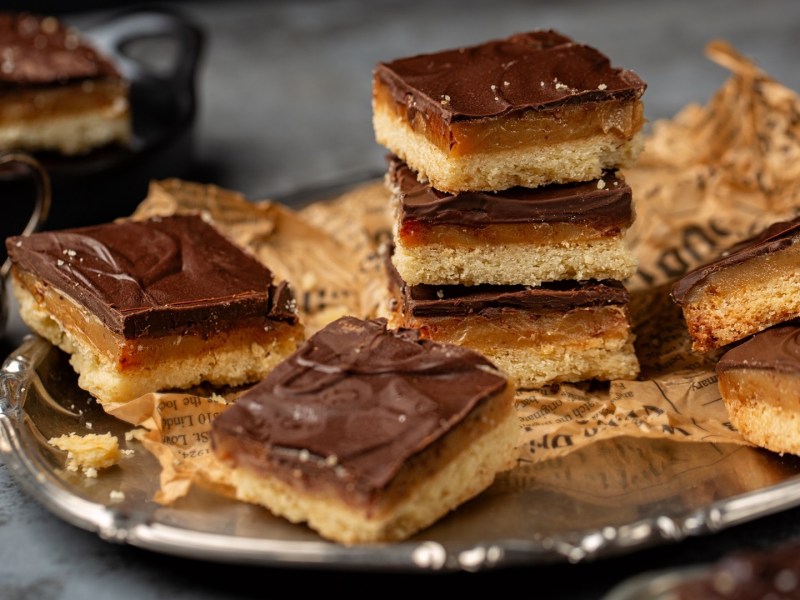 Ein silbernes Tablett mit einem Stapel Millionaire's Shortbread darauf.