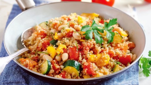 Eine Quinoa-Gemüse-Pfanne mit Zucchini, mit einem Löffel darin.