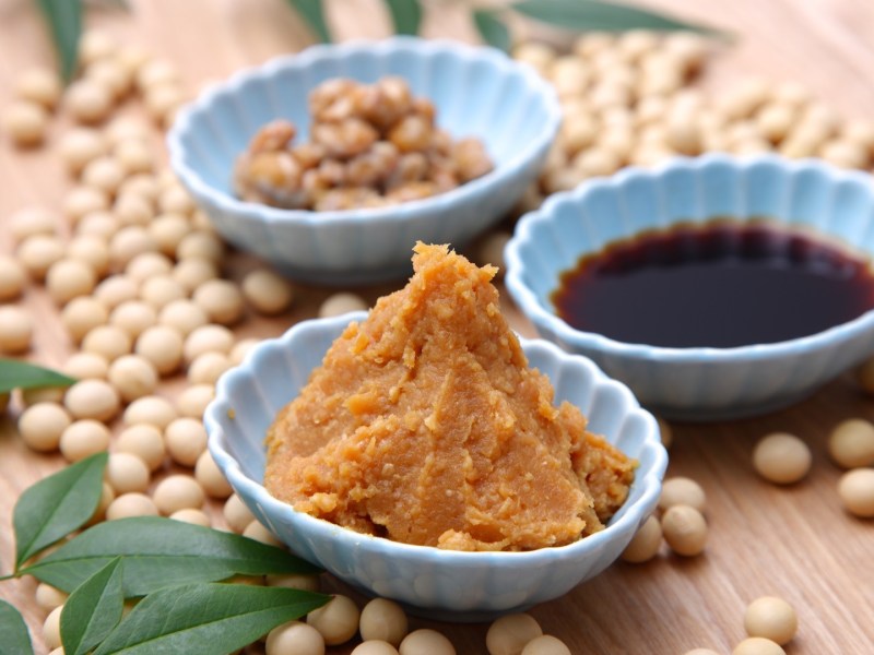 Was ist Miso? Mehrere Schüsseln mit MIso, Sojasoße und Sojabohnen auf einem Holzuntergrund.