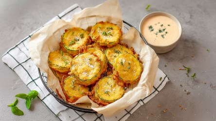 Ein große Schale mit Backpapier ausgelegt. Die Schüssel steht auf einem Küchenhandtuch. Daneben steht eine kleine Schale mit Dip.