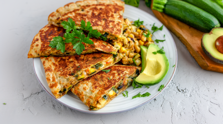 Zucchini-Tortillas auf einem Teller, angerichtet mit Rührei und Avocado.