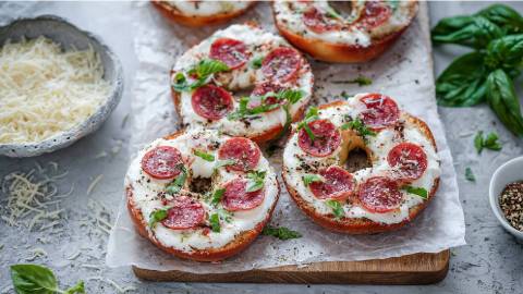 Holzbrett mit 5 Bagel-Pizzen