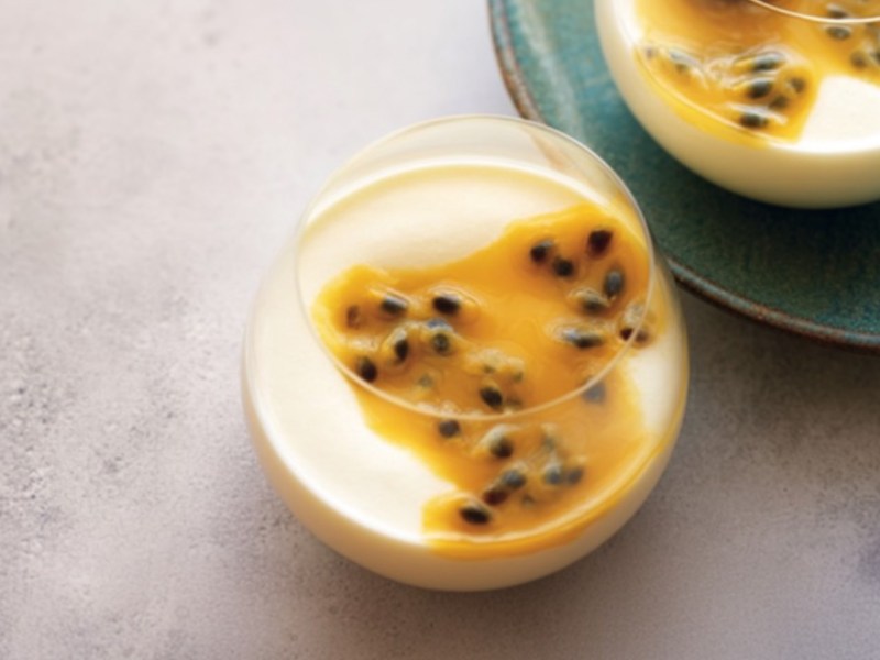 Ein Glas Crème-fraiche-Mousse mit Maracujasoße in der Draufsicht.