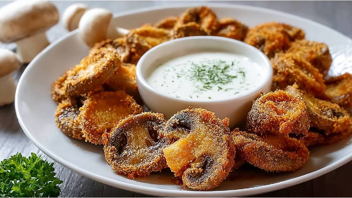 Teller mit frittierten Champignons und einer Schale mit einem Dip daneben