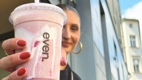 Redakteurin Nina hält einen Erdbeer-Smoothie, der Hailey Bieber's Strawberry Glaze Skin Smoothie ähnelt in die Kamera.