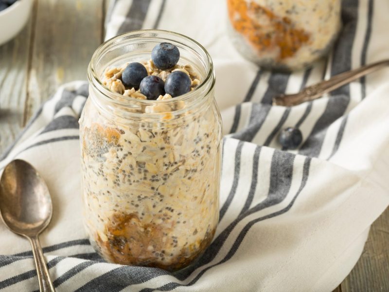 Ein Glas mit Kefir Overnight Oats, serviert mit Blaubeeren.