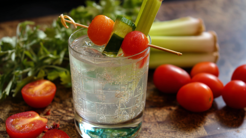 EIn Glas mit klarem Bloody Mary, garniert mit Tomaten, Gurke und Sellerie.