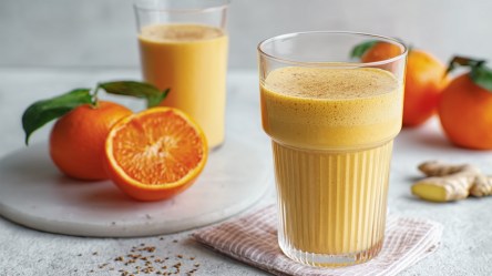 Zwei Gläser Mandarinen-Lassi. Daneben liegen frische früchte.