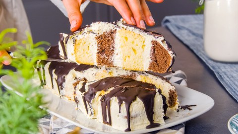 Ein Stück Metrowiec wird in die Kamera gehalten. Dahinter ist der restliche Kuchen zu sehen.
