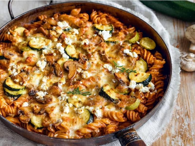 Nudelpfanne mit Champignons und Zucchini auf einem Tisch, Champignons daneben