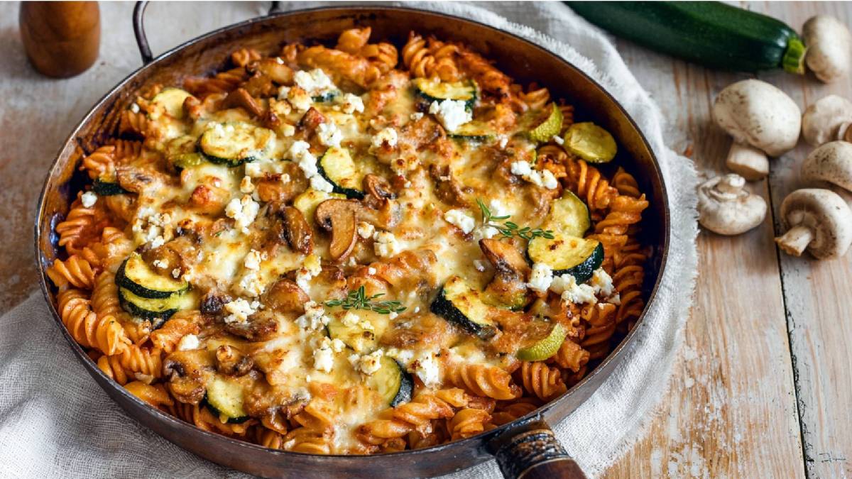 Nudelpfanne mit Champignons und Zucchini auf einem Tisch, Champignons daneben
