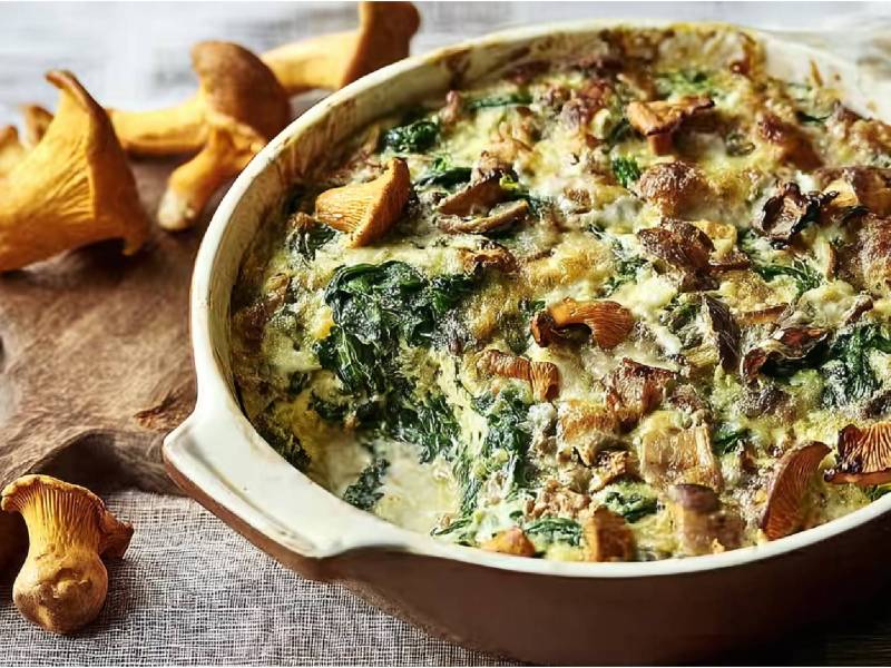 Auflaufform mit Pfifferling-Spinat-Gratin und frischen Pfifferlingen daneben