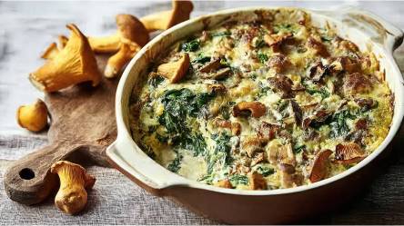 Auflaufform mit Pfifferling-Spinat-Gratin und frischen Pfifferlingen daneben