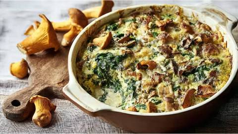 Auflaufform mit Pfifferling-Spinat-Gratin und frischen Pfifferlingen daneben