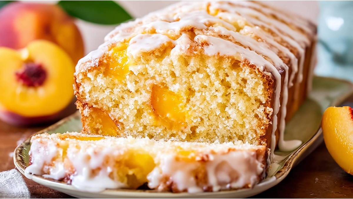 Angeschnittenes Pfirsichbrot auf einem Tisch, Pfirsiche im Hintergrund