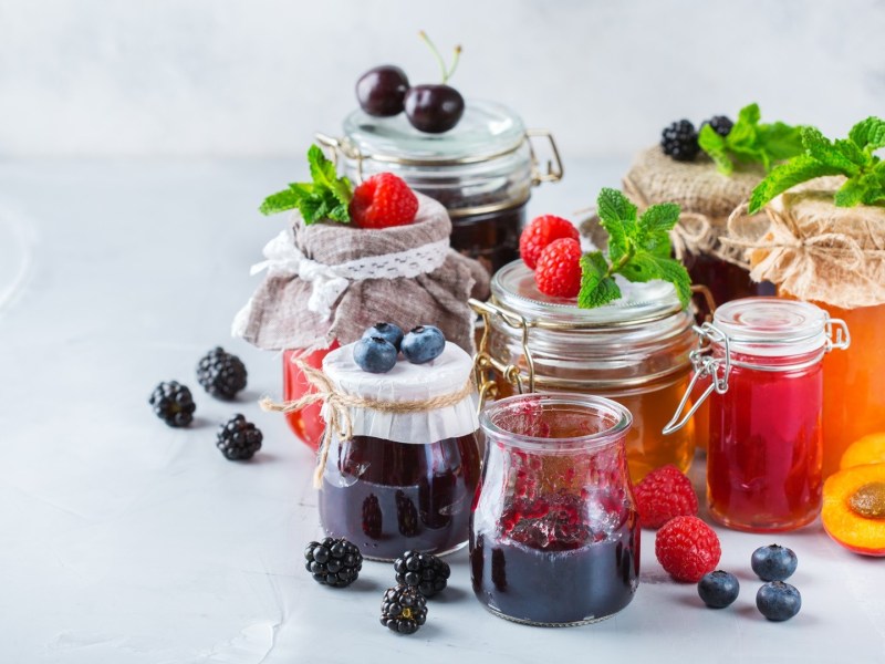 Sommer-Marmeladen: einige Gläser mit Marmelade stehen auf einem hellen Untergrund.