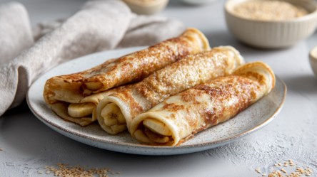 Mehrere gerollte türkische Pfannkuchen mit Bananen-Sesam-Füllung.